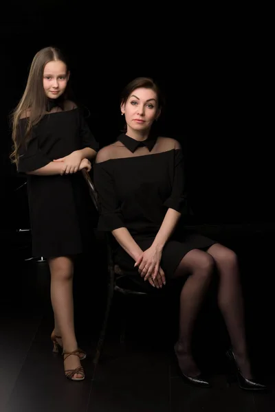 Maman et fille dans le studio sur un fond noir. — Photo