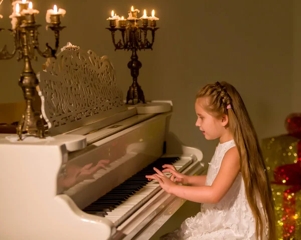 Kleines Mädchen spielt bei Kerzenschein Klavier. — Stockfoto