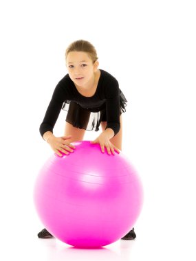 Küçük kız spor yapmak için büyük bir top üzerinde egzersiz yapıyor..