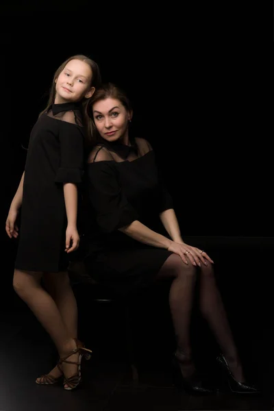 Maman et fille dans le studio sur un fond noir. — Photo