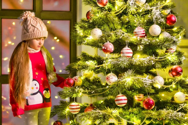 Küçük kız bir Noel ağacını süslüyor. Yeni yıl konsepti, aile tatilleri. — Stok fotoğraf