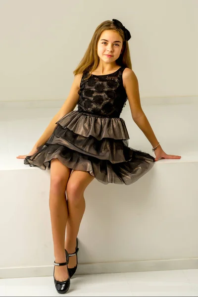 Милая маленькая девочка сидит в студии на белой лестнице. стиль и мода концепции, счастливое детство. — стоковое фото