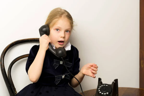 Una niña está sonando en el viejo teléfono. —  Fotos de Stock