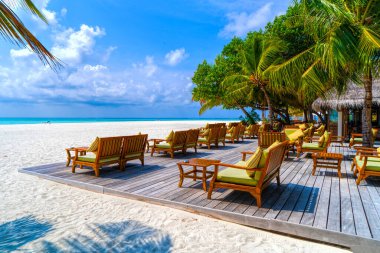 Tahta masa ve tropik ılık denizin yanındaki sandalyeler. Maldivler