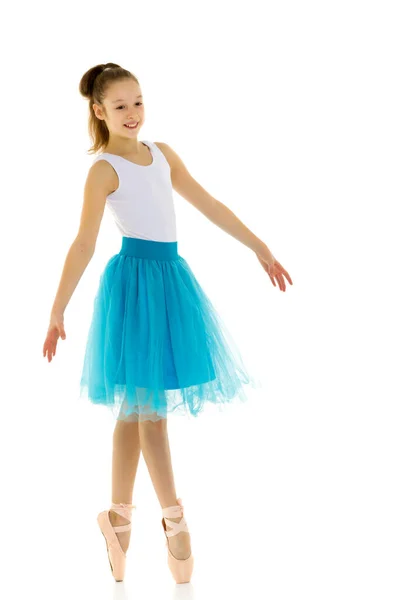 Söt liten flicka i en tutu och pointe skor dans i studion på en vit bakgrund. — Stockfoto