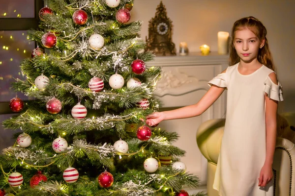 Menina em vestido elegante Sentado no chão na frente da árvore de Natal. — Fotografia de Stock