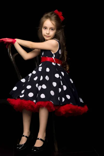 Bella ragazza in Polka Dot Dress seduto su sfondo nero isolato. — Foto Stock