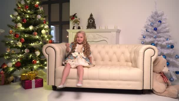 Niña con bengala bajo el árbol de Navidad en la víspera de Navidad en casa. — Vídeos de Stock