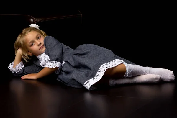 Cute little girl leżące na podłodze w studio na czarnym tle — Zdjęcie stockowe