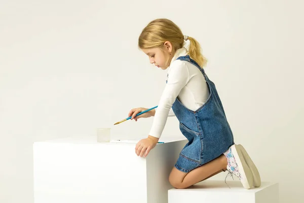 Cute Blonde Girl Sitting on Her Knees and Painting with Brush. — Stock Photo, Image