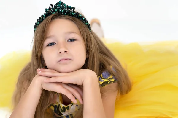 Uma menina está deitada no chão. Sessão de fotos de estúdio em um fundo branco. — Fotografia de Stock