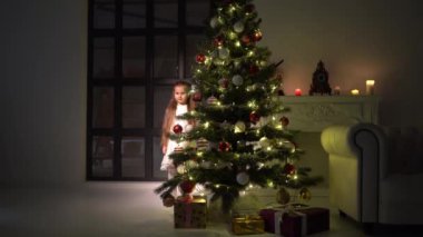 Küçük kız bir Noel ağacını süslüyor. Yeni yıl konsepti, aile tatilleri.