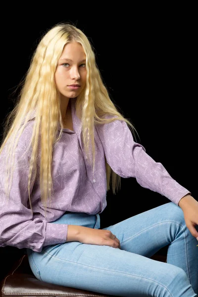 Nahaufnahme des süßen lächelnden blonden Mädchens, das auf schwarzem Hintergrund posiert — Stockfoto