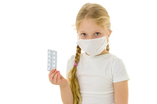 Kleines Mädchen in medizinischer Maske. Sie hält eine Packung Tabletten in der Hand. Krankheitskonzept, covid-19. — Stockfoto