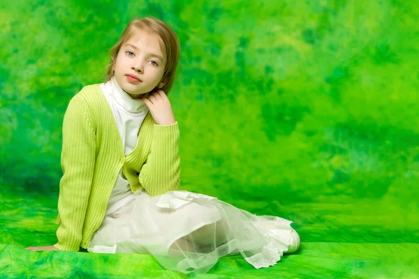 Nahaufnahme, auf grünem Hintergrund das Porträt eines schönen kleinen Mädchens. — Stockfoto