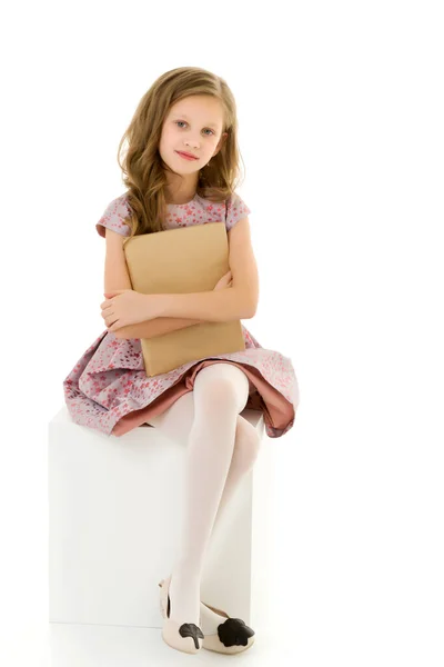 Beautiful Girl Sitting on White Cube and Hugging Book — Stock Photo, Image
