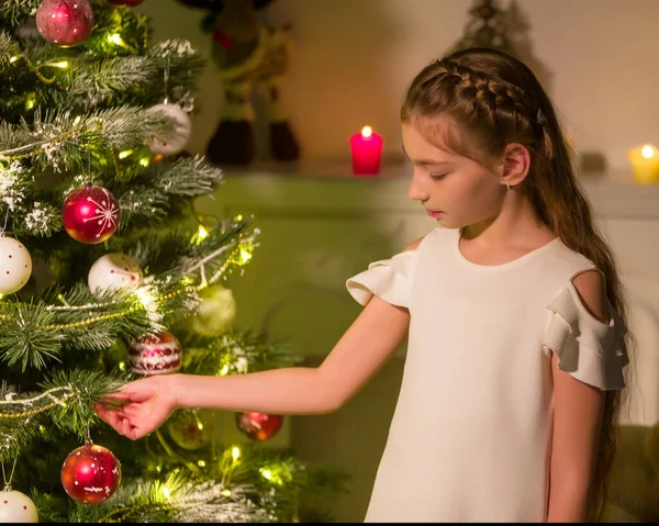 Chica en vestido elegante sentada en el suelo delante del árbol de Navidad. —  Fotos de Stock