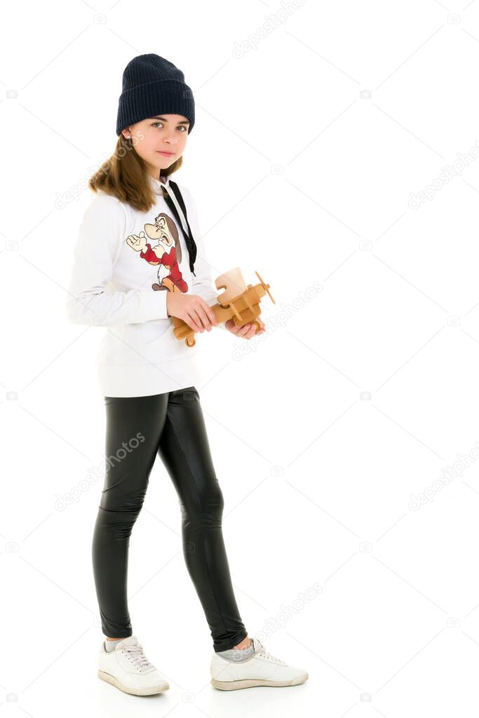 Little girl is playing with a wooden plane.