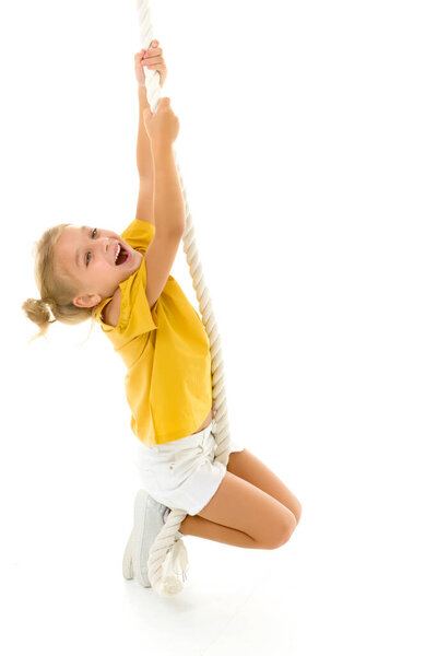 A little girl holds on to the rope with her hands, swinging on it.