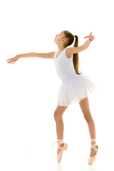 Schattig klein meisje in een tutu en pointe schoenen dansen in de studio op een witte achtergrond. — Stockfoto