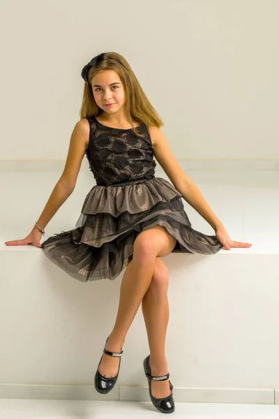 Linda niña está sentada en el estudio en las escaleras blancas. estilo y concepto de moda, infancia feliz. —  Fotos de Stock