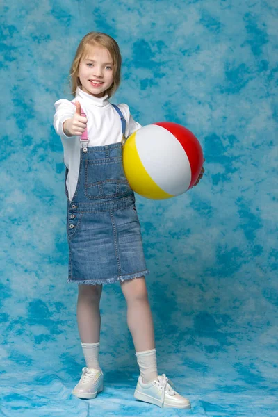 A kislány egy labdával játszik.A gyermeksportok koncepciója, nyári szabadtéri kikapcsolódás. — Stock Fotó