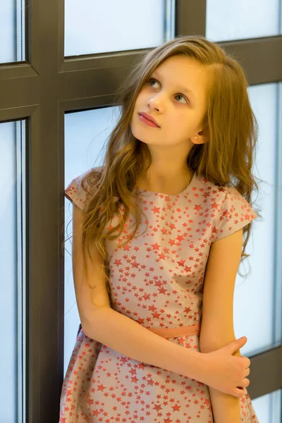 Menina séria bonita em pé perto de parede de vidro olhando para cima — Fotografia de Stock