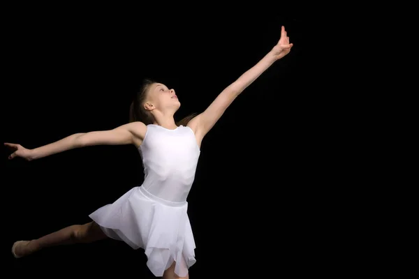 Linda niña en un tutú y zapatos puntiagudos está bailando en el estudio sobre un fondo negro. —  Fotos de Stock