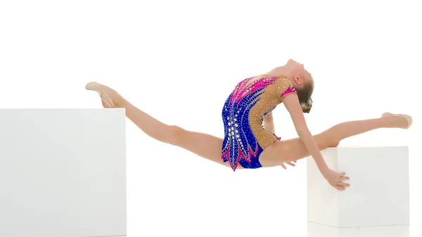 Hermosa chica gimnasta en un cubo blanco hace un elemento de cordel acrobático. —  Fotos de Stock