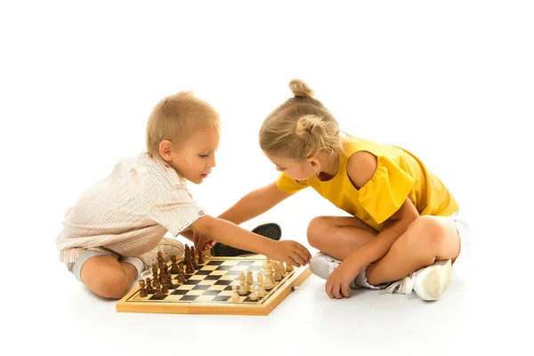 Niño y niña pensativos se sientan en el suelo y juegan al ajedrez. — Foto de Stock