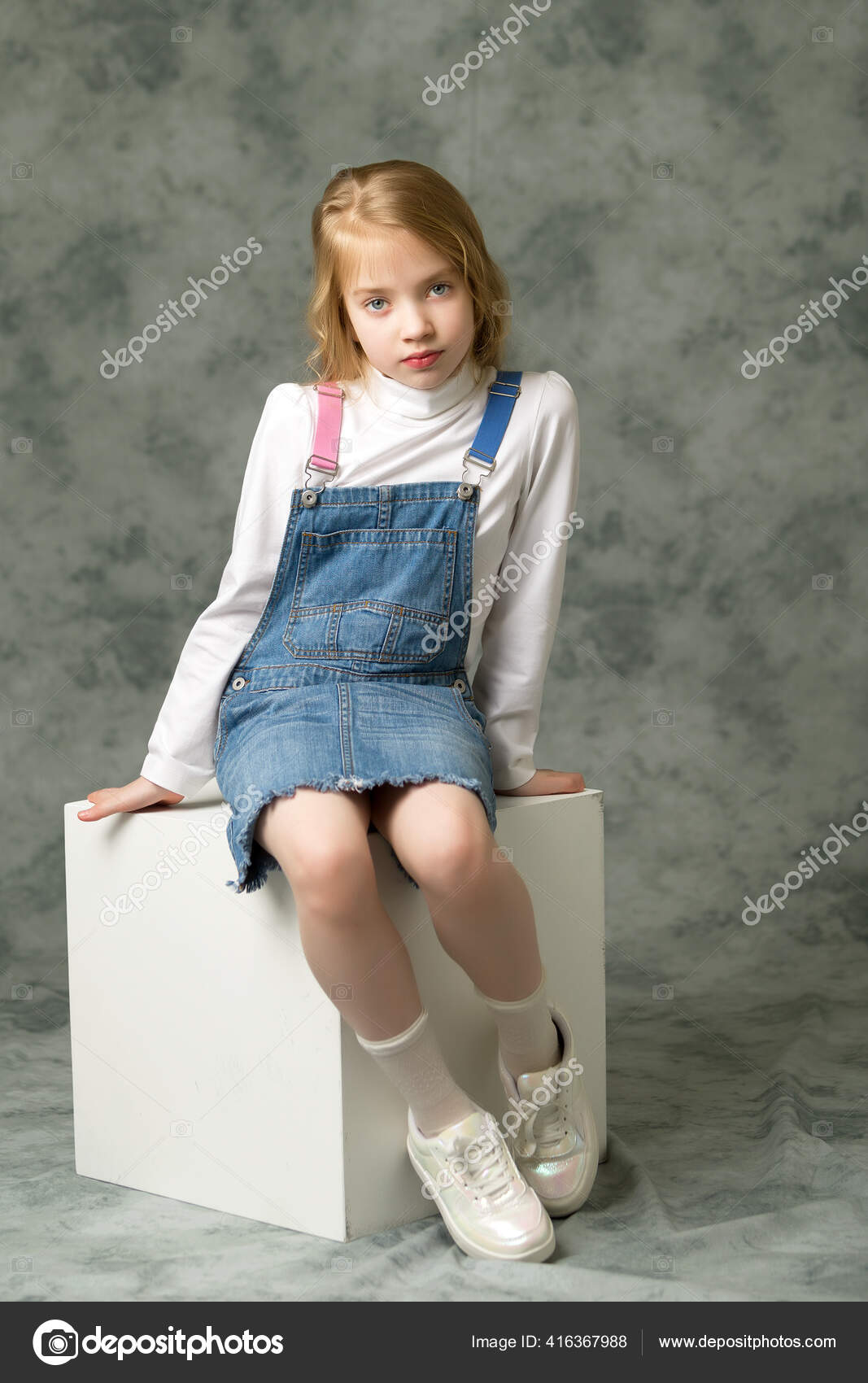 Little girl in a short denim dress. Stock Photo by ©lotosfoto1