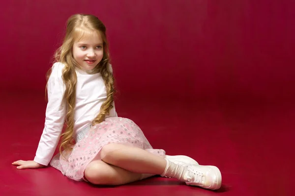 La niña está sentada en el suelo.El concepto de un niño feliz — Foto de Stock