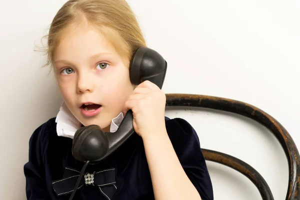 Una niña está sonando en el viejo teléfono. —  Fotos de Stock