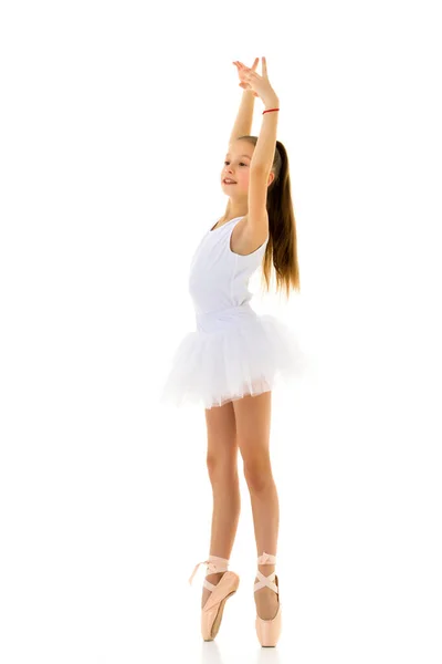Милая маленькая девочка в пачке и пуантах танцует в студии на белом фоне. — стоковое фото