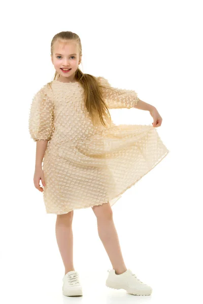 Een klein meisje houdt haar handen aan de randen van de rok. — Stockfoto