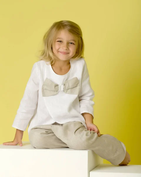 Bella ragazza sorridente seduta sul cubo bianco sulle ginocchia. — Foto Stock