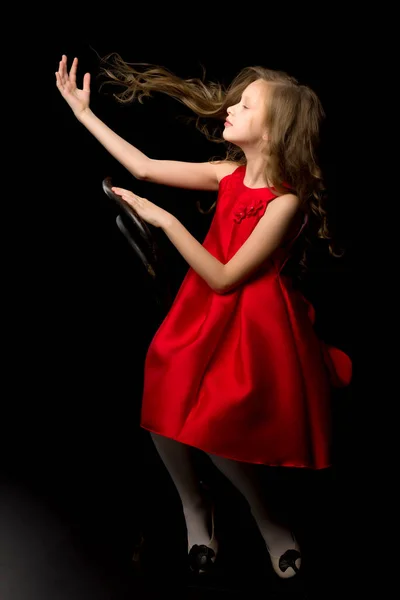 Вдохновленная девушка в красном платье, сидящая на парике — стоковое фото