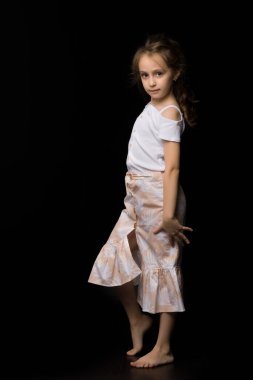 Güzel bir kız başını eğmiş kameraya gülümsüyor, şık giyinmiş güzel bir çocuk beyaz bir stüdyoda poz veriyor.