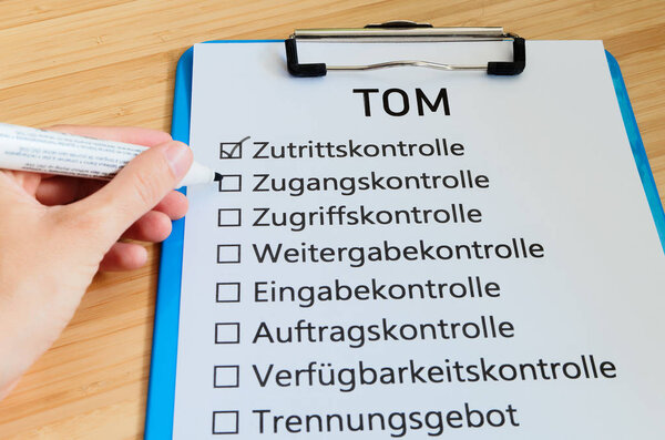 Plate with the inscription TOM (Technisch organisatorische Massnahmen)  in English Technically organizational measures with a tablet and block to signal typical activities of data protection officers