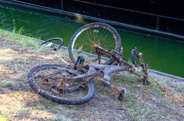Yasadışı yollardan bertaraf çöp nehir ve denizin göstermek için bir nehir atılmış eski paslı bisiklet