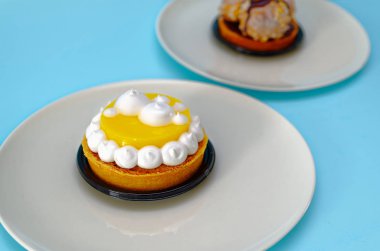 İki pasta parçacıklar limon ve açık mavi renkli ile bir pasta şefi tarafından iki beyaz tabak çikolata