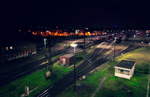 Freight yard at night with grass tracks and parked trains for maneuvering