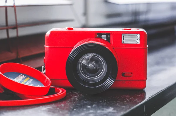 Lifestyle camera in rot with exposed instant films and drotty headphones on a bamboo table