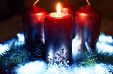 Advent çelenk ile arka plan olarak kar kırmızı altın mumlar ve henüz yanan mumlar