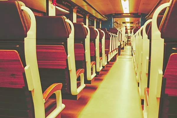 Train seats in a train compartment in white optic with wood at a train station at night