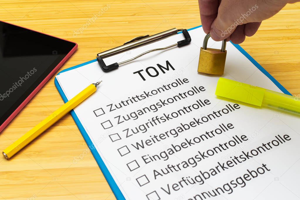 Plate with the inscription TOM Technisch organisatorische Manahmen  in English Technically organizational measures with a tablet and block to signal typical activities of data protection officers