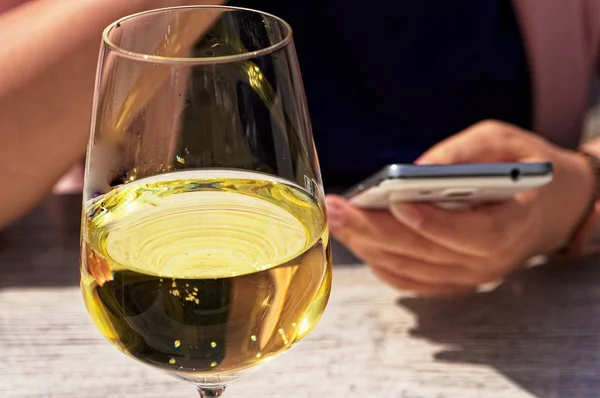 Γυναίκα Που Χρησιμοποιεί Κινητό Τηλέφωνο Μπροστά Από Ένα Ποτήρι Κρασί — Φωτογραφία Αρχείου
