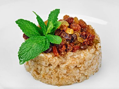 Üzümlü tam tahıllı yulaf ezmesi ve beyaz arka planda izole edilmiş nane yaprakları.