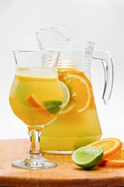 Taze meyve, buz, nane yaprağı ve kavanozla beyaz arka planda izole edilmiş bir bardak portakal suyu.