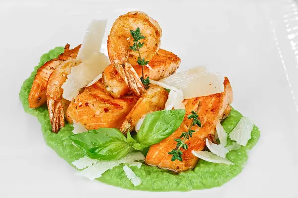 Pişmiş kırmızı balık bifteği ve sert peynirli kızarmış karides. Beyaz üzerine yeşil püre brokoli püresi.